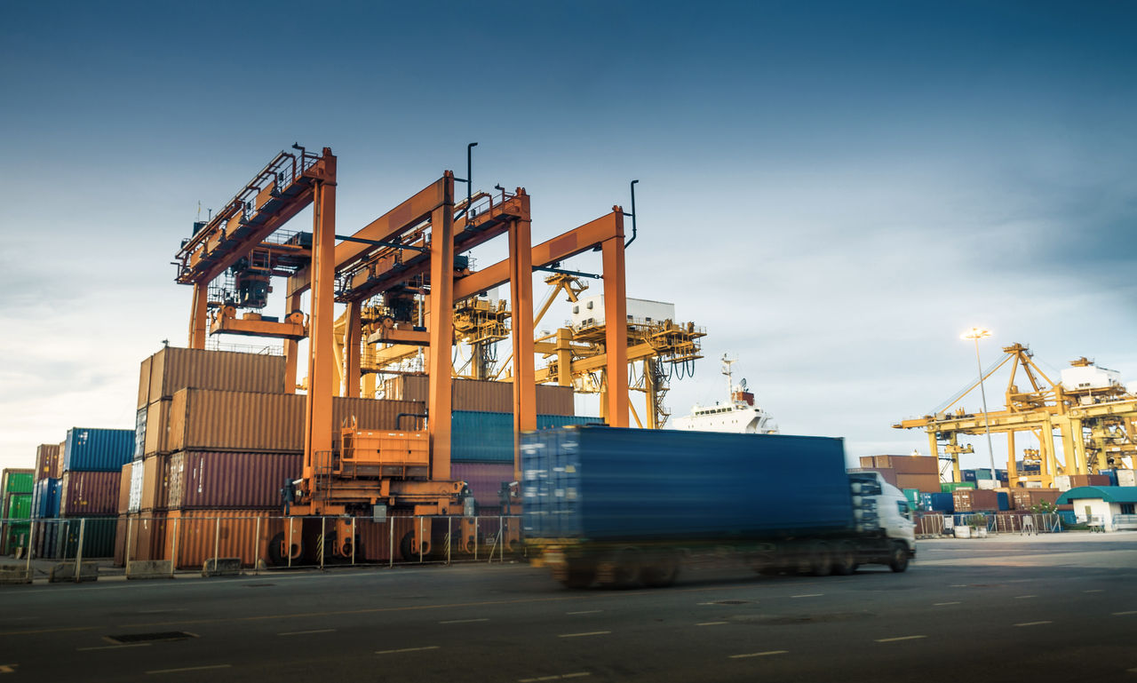 Container crane in harbor and Semperit truck driving in front making it a slow shutter image. 